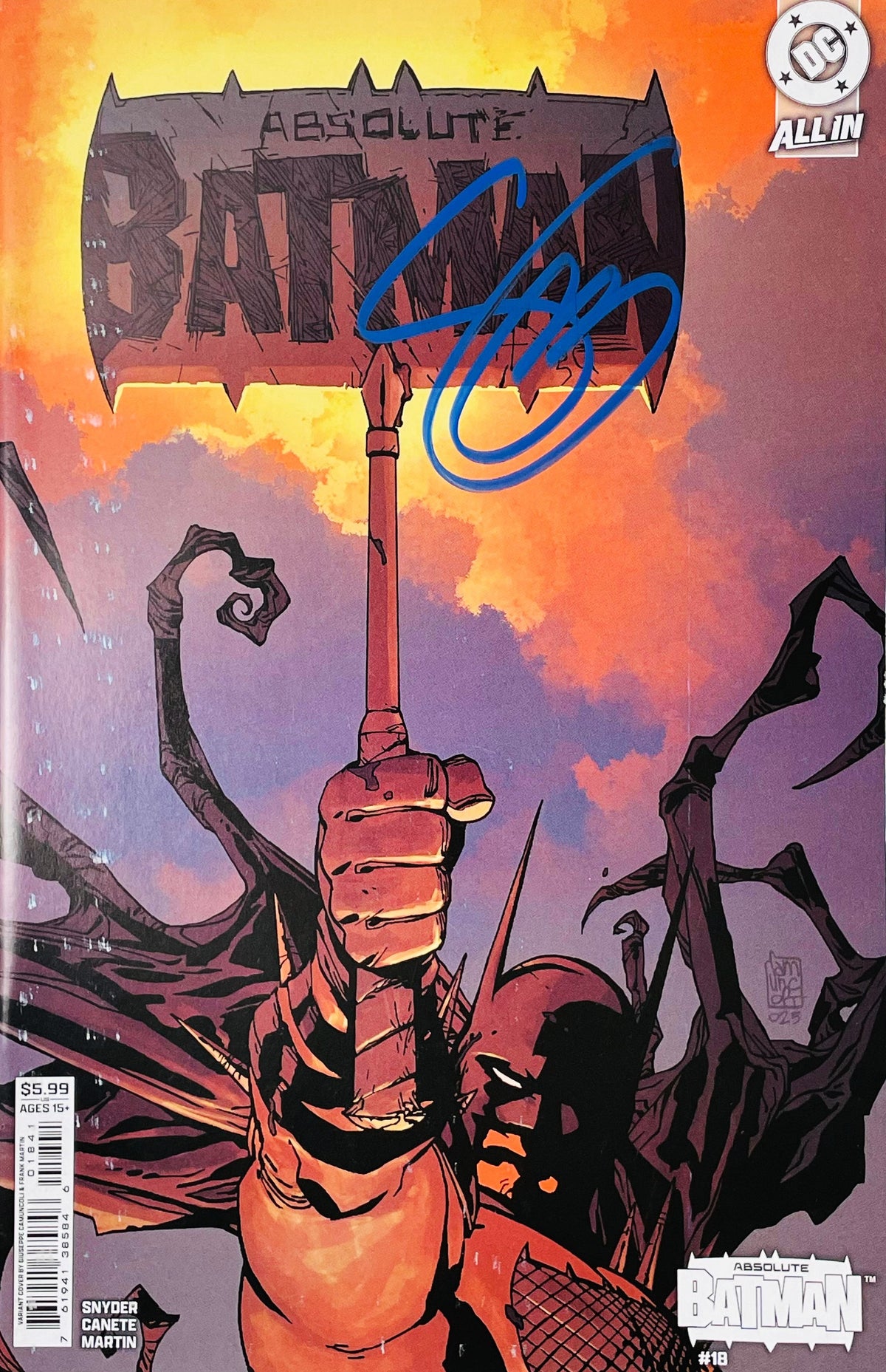 Signed Absolute Batman issue 18 variant cover by Giuseppe Camuncoli showing Batman holding up his axe emblem with a blue signature across the logo.