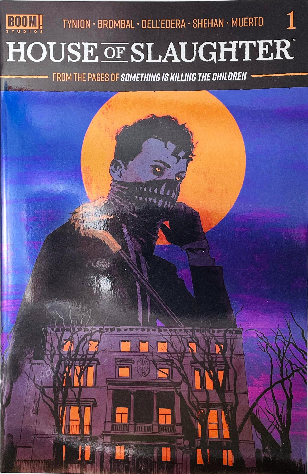 House of Slaughter issue 1 comic book published by BOOM Studios featuring Chris Shehan cover art of Aaron Slaughter in a tooth mask standing over a glowing mansion under an orange moon.