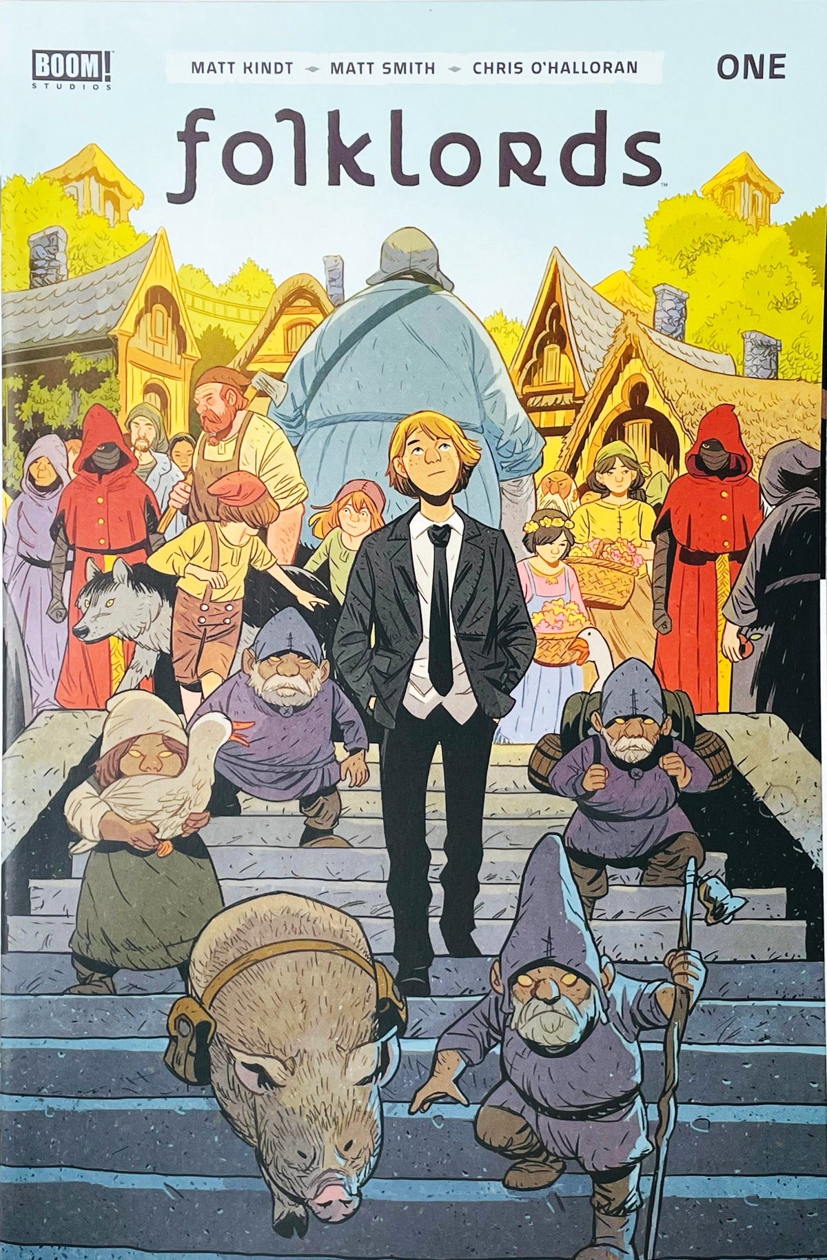 Folklords issue 1 comic book published by BOOM Studios featuring Matt Smith cover art of Ansel in a suit walking through a fairytale village with gnomes and creatures.