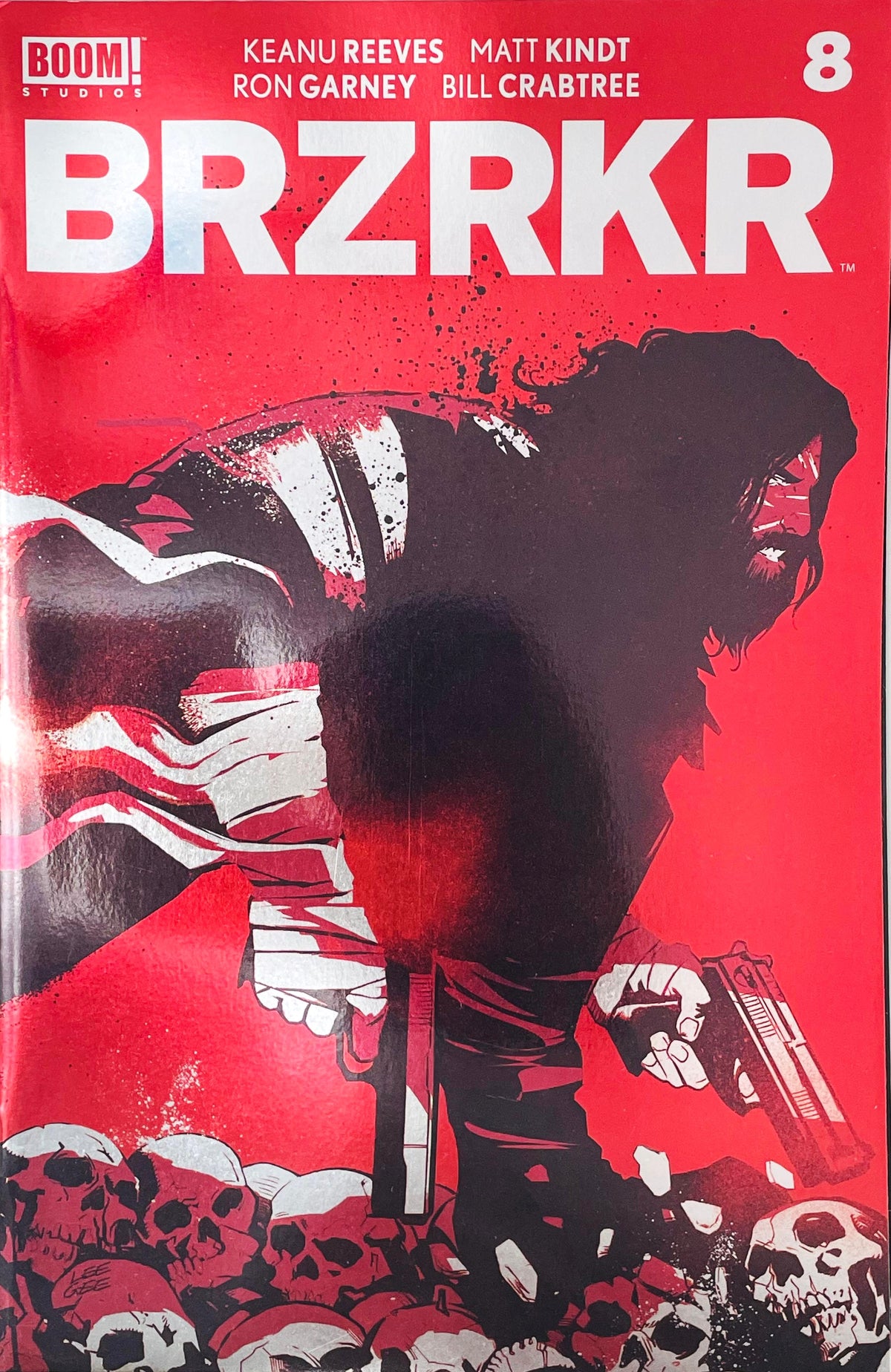 BRZRKR issue 8 comic book published by BOOM Studios featuring Lee Garbett foil variant cover art of Keanu Reeves immortal character B dual wielding handguns over skulls.