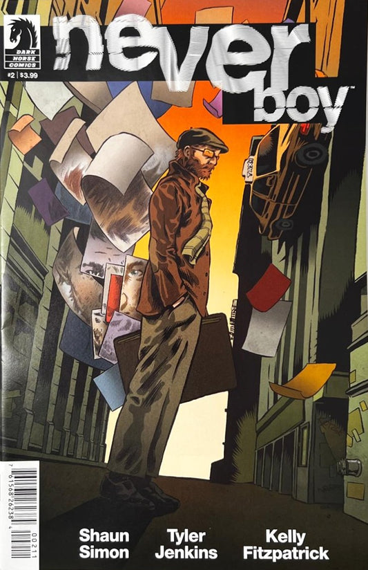 Neverboy issue 2 comic book published by Dark Horse Comics featuring Tyler Jenkins cover art of a man carrying a case as reality warps and artwork pages float around him.