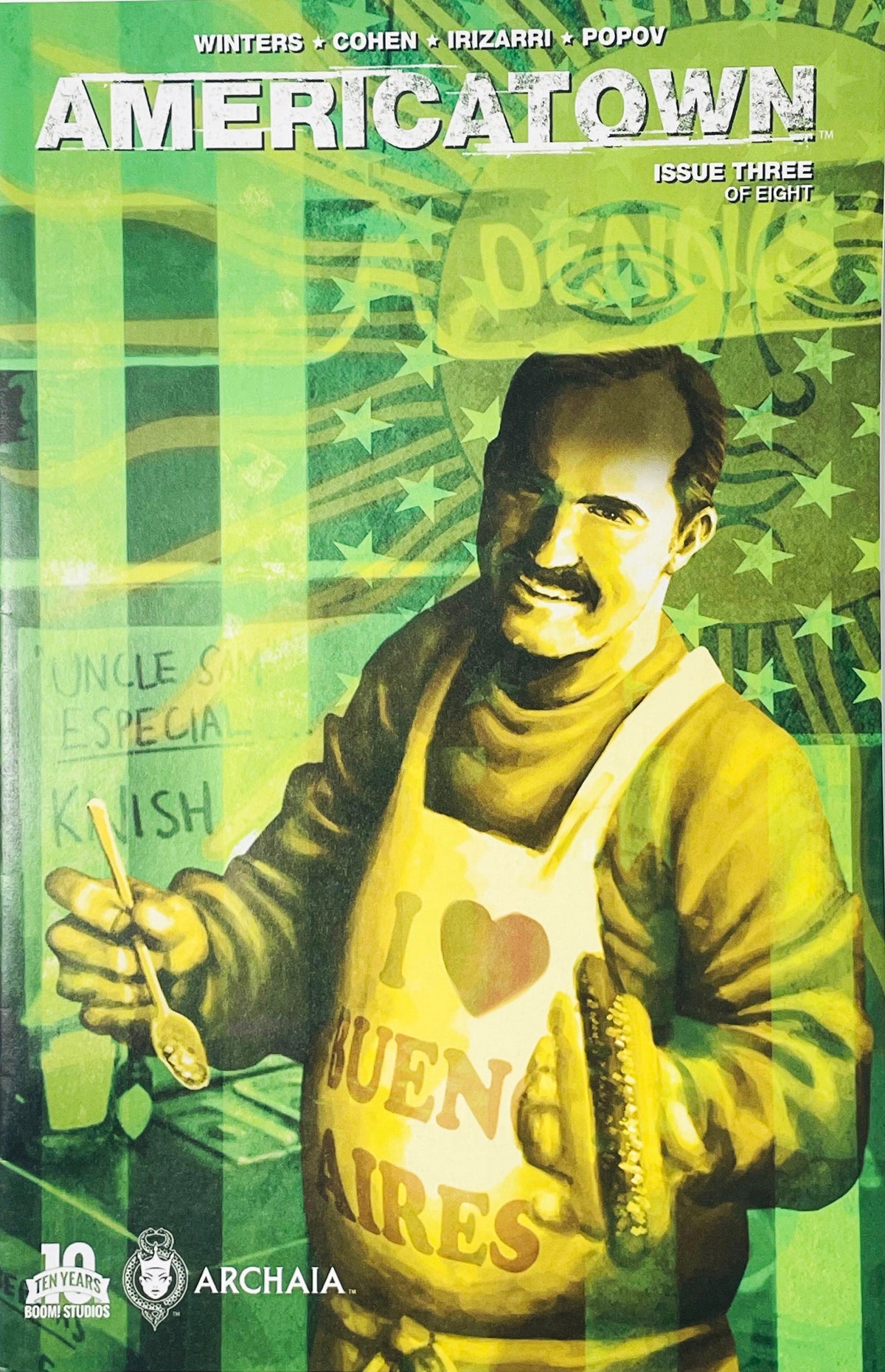 Smiling man in an I Love Buenos Aires apron holding a spoon on green-tinted cover of Americatown issue 3.